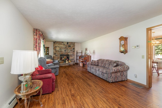 5772 Greensboro Way, Gladwin, MI 48624 - living area featuring a baseboard radiator, wood finished floors, a textured ceiling, and a stone fireplace
