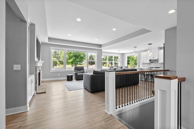 1560 Marksbury Ct, Byron Center, MI 49315 - living room with plenty of natural light, light wood finished floors, a fireplace, recessed lighting, and a tray ceiling