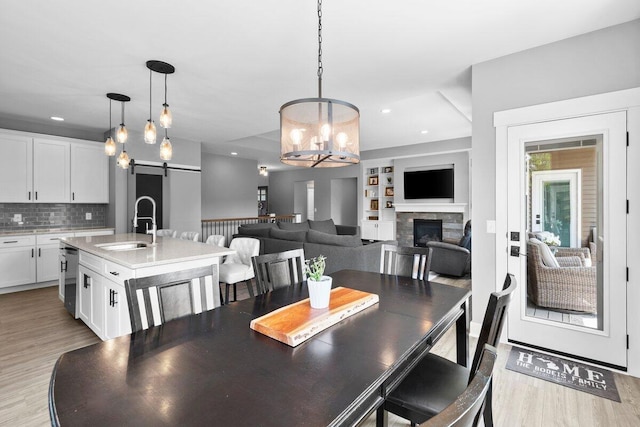 1560 Marksbury Ct, Byron Center, MI 49315 - dining room featuring a barn door, light wood-style flooring, a chandelier, a stone fireplace, and built in shelves