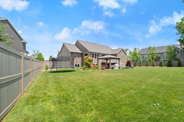 1560 Marksbury Ct, Byron Center, MI 49315 - rear view of house featuring a trampoline, a gazebo, and a fenced backyard