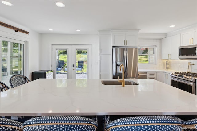 4294 N E Torch Lake Dr, Central Lake, MI 49622 - kitchen featuring stainless steel appliances, french doors, an island with sink, light stone counters, and recessed lighting