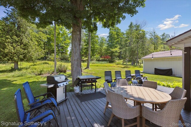 4294 N E Torch Lake Dr, Central Lake, MI 49622 - deck featuring grilling area, a lawn, outdoor dining space, and view of scattered trees
