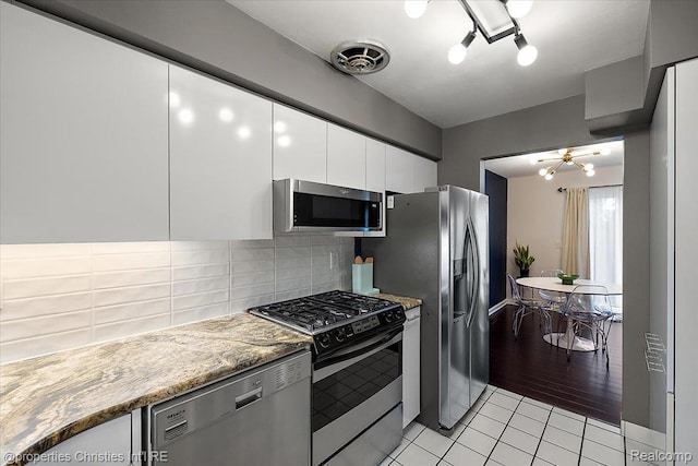 1982 Wickham St, Royal Oak, MI 48073 - kitchen featuring appliances with stainless steel finishes, white cabinetry, backsplash, light tile patterned floors, and a chandelier