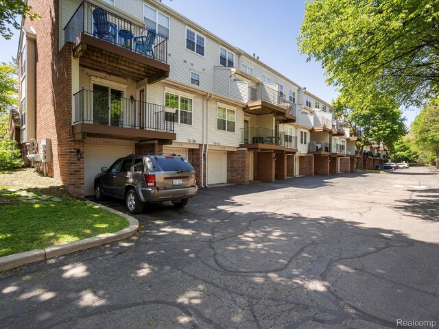 1524 Maryland Club Dr, Royal Oak, MI 48067 - back of house featuring a residential view, brick siding, an attached garage, driveway, and a balcony