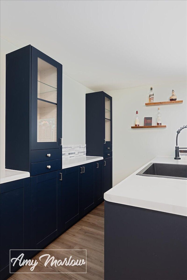 708 Magnolia Ct, Big Rapids, MI 49307 - kitchen featuring blue cabinetry, glass insert cabinets, wood finished floors, and light countertops