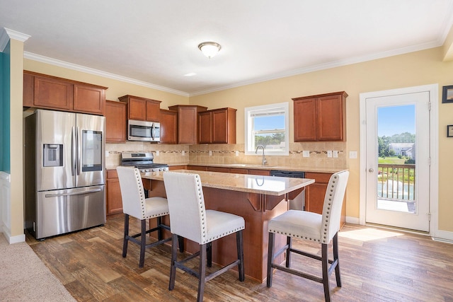 9330 Windward Dr, West Olive, MI 49460 - kitchen with appliances with stainless steel finishes, dark wood-style floors, a center island, a breakfast bar area, and crown molding
