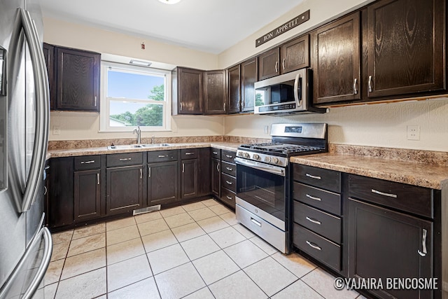2751 Valley Ave NW, Grand Rapids, MI 49544 - kitchen with appliances with stainless steel finishes, dark brown cabinetry, light tile patterned flooring, and light countertops