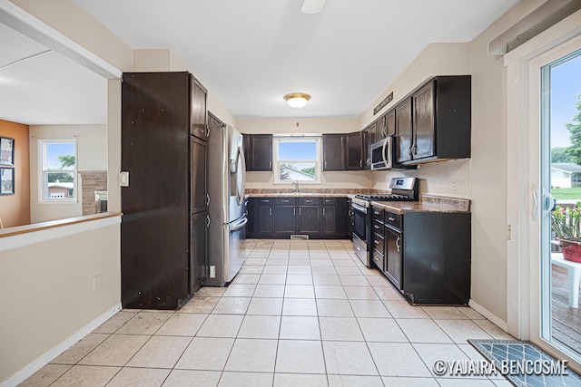 2751 Valley Ave NW, Grand Rapids, MI 49544 - kitchen with stainless steel appliances, light tile patterned floors, and dark brown cabinets