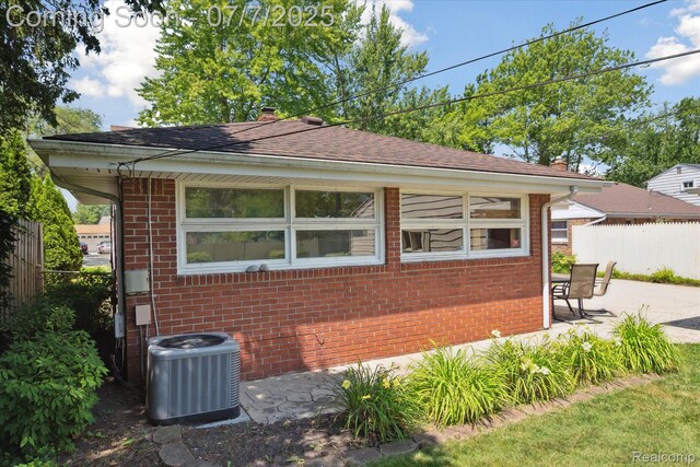 18735 Valade St, Riverview, MI 48193 - view of side of home featuring brick siding, a patio, roof with shingles, and a chimney