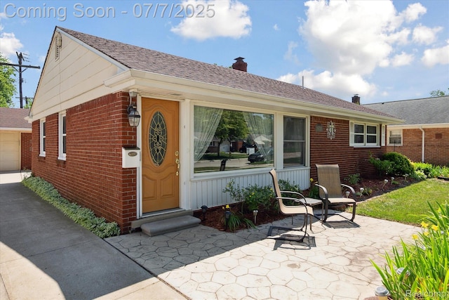 18735 Valade St, Riverview, MI 48193 - doorway to property featuring brick siding, a chimney, and a patio