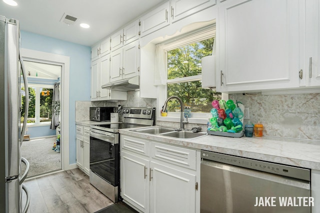 816 Malta St NE, Grand Rapids, MI 49503 - kitchen featuring appliances with stainless steel finishes, light wood-style flooring, light countertops, white cabinets, and plenty of natural light