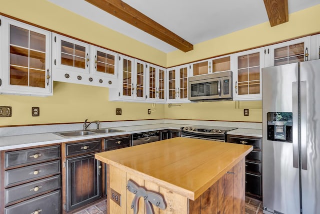 1007 Oak Grove Rd, Jackson, MI 49203 - kitchen with stainless steel appliances, a kitchen island, beam ceiling, brick patterned flooring, and glass insert cabinets
