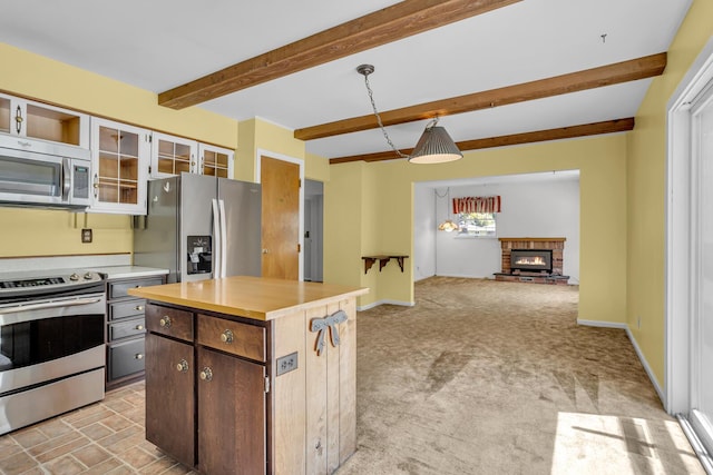 1007 Oak Grove Rd, Jackson, MI 49203 - kitchen featuring appliances with stainless steel finishes, light countertops, glass insert cabinets, a fireplace, and beamed ceiling