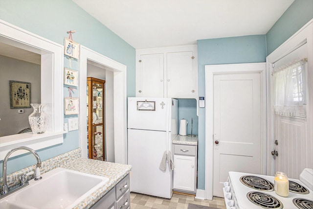 618 Madison St, Jackson, MI 49202 - kitchen featuring freestanding refrigerator, range, light countertops, and white cabinetry