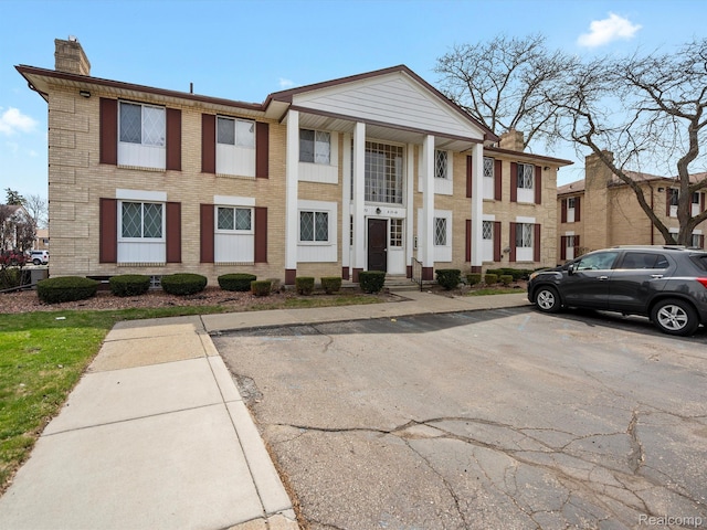 29272 Gloede Dr Unit 16, Warren, MI 48088 - view of front facade featuring a chimney, uncovered parking, and brick siding