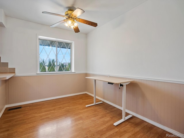 29272 Gloede Dr Unit 16, Warren, MI 48088 - empty room with light wood-style flooring, a wainscoted wall, and a ceiling fan