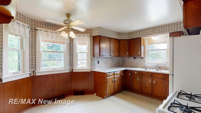 508 Malzahn St, Saginaw, MI 48602 - kitchen featuring freestanding refrigerator, light countertops, brown cabinets, ceiling fan, and wallpapered walls