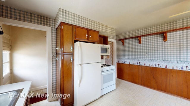 508 Malzahn St, Saginaw, MI 48602 - kitchen featuring white appliances, wallpapered walls, brown cabinetry, and light countertops