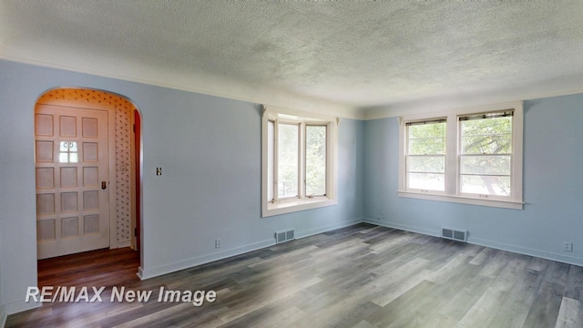 508 Malzahn St, Saginaw, MI 48602 - spare room featuring a textured ceiling, arched walkways, and wood finished floors
