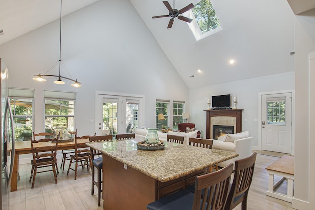 488 Solace Way S, Haven, MI 49090 - kitchen featuring high vaulted ceiling, a tiled fireplace, a breakfast bar, a ceiling fan, and light wood finished floors