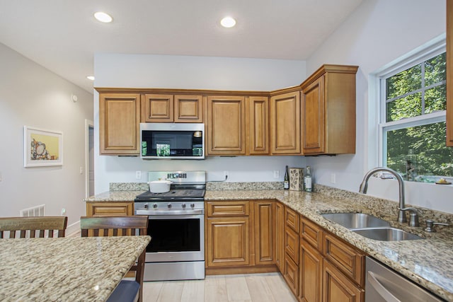 488 Solace Way S, Haven, MI 49090 - kitchen featuring appliances with stainless steel finishes, brown cabinets, light stone countertops, recessed lighting, and light wood-type flooring