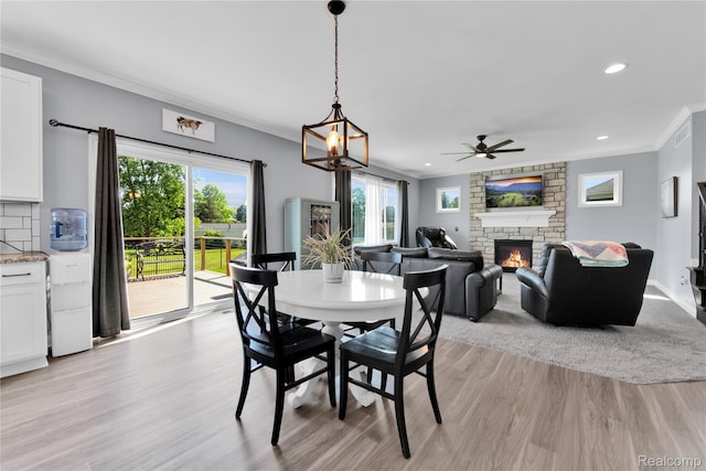 343 Hidden Riv E, Holly, MI 48442 - dining room featuring ornamental molding, a fireplace, light wood-style floors, plenty of natural light, and a ceiling fan