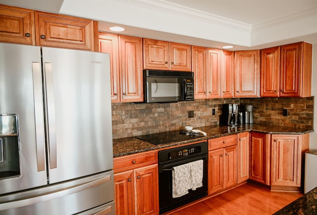 706 N Dockside Cir, Suttons Bay, MI 49682 - kitchen with black appliances, crown molding, light wood-style floors, backsplash, and dark stone countertops