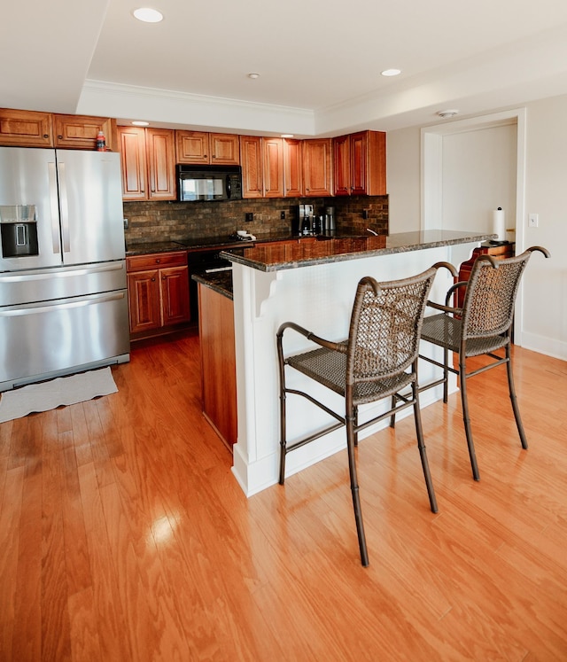 706 N Dockside Cir, Suttons Bay, MI 49682 - kitchen featuring stainless steel fridge, black microwave, a kitchen breakfast bar, light wood-type flooring, and recessed lighting