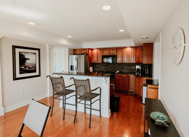706 N Dockside Cir, Suttons Bay, MI 49682 - kitchen with stainless steel refrigerator with ice dispenser, black microwave, a kitchen breakfast bar, a center island, and backsplash