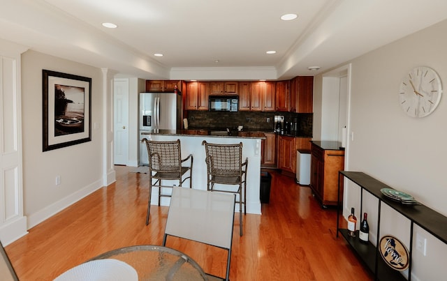706 N Dockside Cir, Suttons Bay, MI 49682 - kitchen with black microwave, stainless steel fridge, dark countertops, backsplash, and wood finished floors