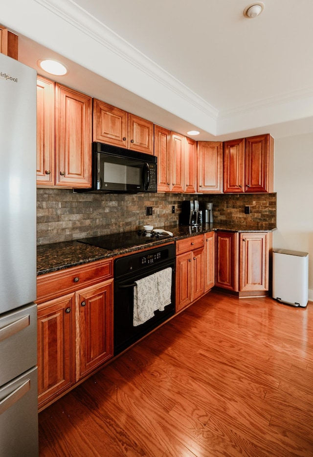 706 N Dockside Cir, Suttons Bay, MI 49682 - kitchen featuring black appliances, crown molding, tasteful backsplash, dark stone counters, and wood finished floors