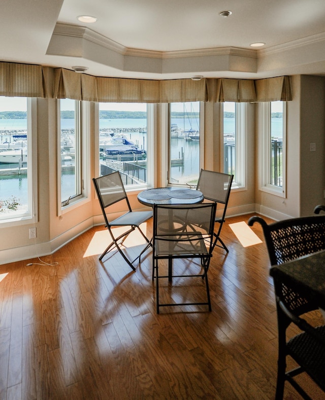 706 N Dockside Cir, Suttons Bay, MI 49682 - dining room featuring ornamental molding, wood finished floors, a water view, a tray ceiling, and recessed lighting