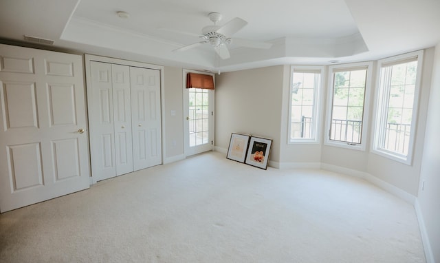 706 N Dockside Cir, Suttons Bay, MI 49682 - unfurnished bedroom with a tray ceiling, carpet, crown molding, a closet, and a ceiling fan