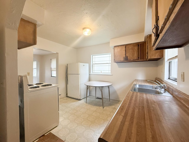 207 W Railroad St, Dowagiac, MI 49047 - kitchen with white appliances, light floors, brown cabinetry, and healthy amount of natural light