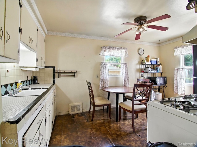 1225 S Annabelle St, Detroit, MI 48217 - kitchen featuring black microwave, a ceiling fan, stove, crown molding, and backsplash
