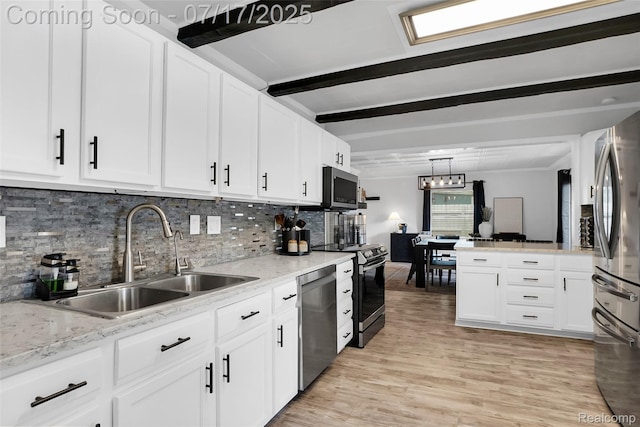 1890 Darwin Rd, Pinckney, MI 48169 - kitchen featuring beam ceiling, stainless steel appliances, light wood-style floors, white cabinets, and backsplash
