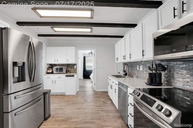 1890 Darwin Rd, Pinckney, MI 48169 - kitchen featuring appliances with stainless steel finishes, backsplash, white cabinetry, light wood-type flooring, and beamed ceiling