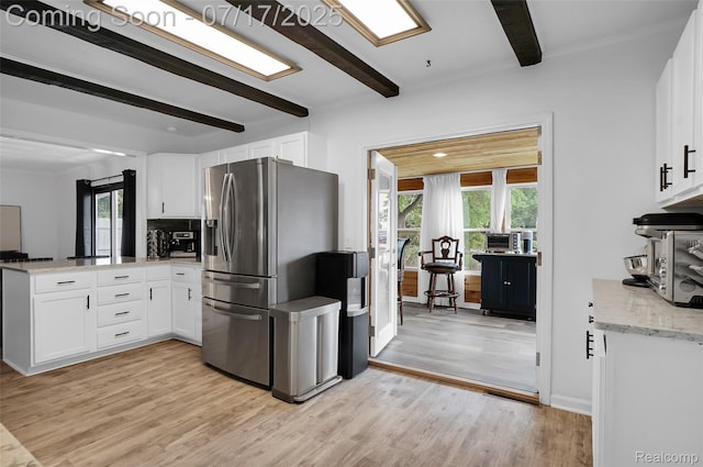 1890 Darwin Rd, Pinckney, MI 48169 - kitchen with stainless steel fridge with ice dispenser, a peninsula, beamed ceiling, healthy amount of natural light, and light wood-style flooring