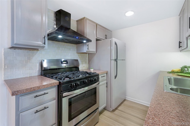 9671 Harbour Cove Ct, Ypsilanti, MI 48197 - kitchen with stainless steel range with gas cooktop, wall chimney range hood, light wood-type flooring, tasteful backsplash, and freestanding refrigerator