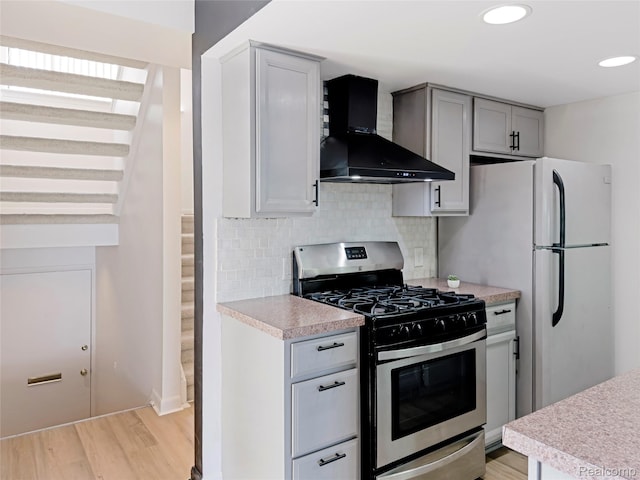 9671 Harbour Cove Ct, Ypsilanti, MI 48197 - kitchen with stainless steel range with gas cooktop, wall chimney range hood, light countertops, light wood-style floors, and recessed lighting