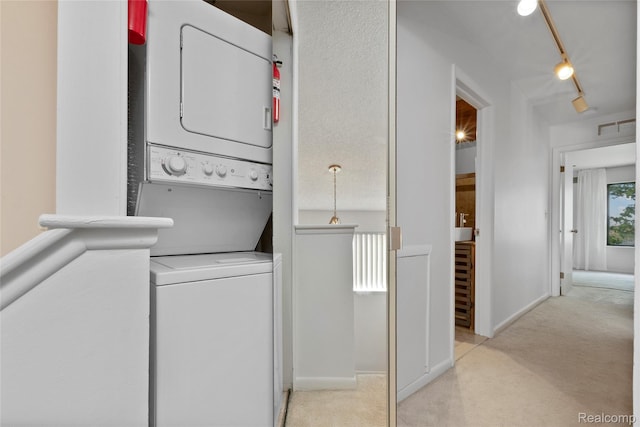 9671 Harbour Cove Ct, Ypsilanti, MI 48197 - washroom with stacked washing machine and dryer, light carpet, and rail lighting
