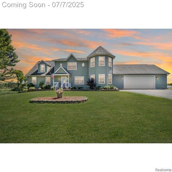 1090 E Jones Rd, Howell, MI 48855 - view of front of house with driveway, a yard, and an attached garage