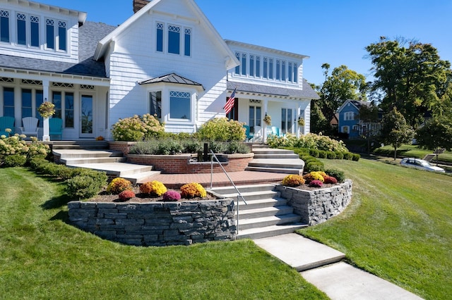 613 E Mitchell St, Petoskey, MI 49770 - view of front facade with a shingled roof, a front yard, a chimney, and a standing seam roof