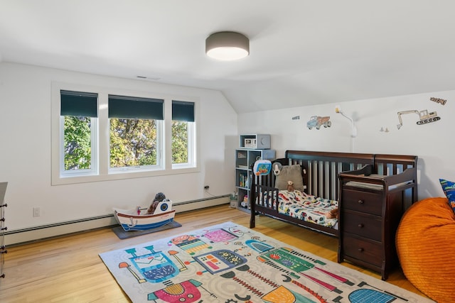 613 E Mitchell St, Petoskey, MI 49770 - bedroom with a baseboard heating unit, wood finished floors, and vaulted ceiling