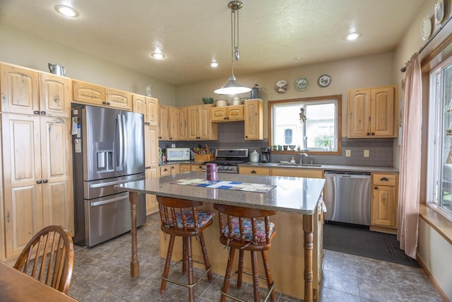 11105 Hahn Beach Dr, Evart, MI 49631 - kitchen with stainless steel appliances, a kitchen island, a kitchen breakfast bar, light brown cabinetry, and recessed lighting