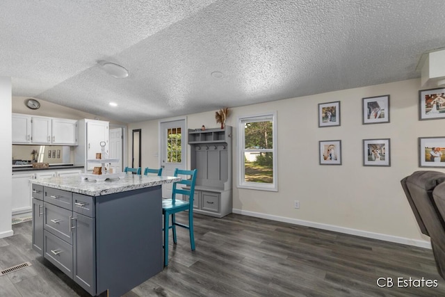 4301 Lasalle Ln, Newaygo, MI 49337 - kitchen featuring a kitchen bar, a kitchen island, dark wood-style floors, a textured ceiling, and white cabinets