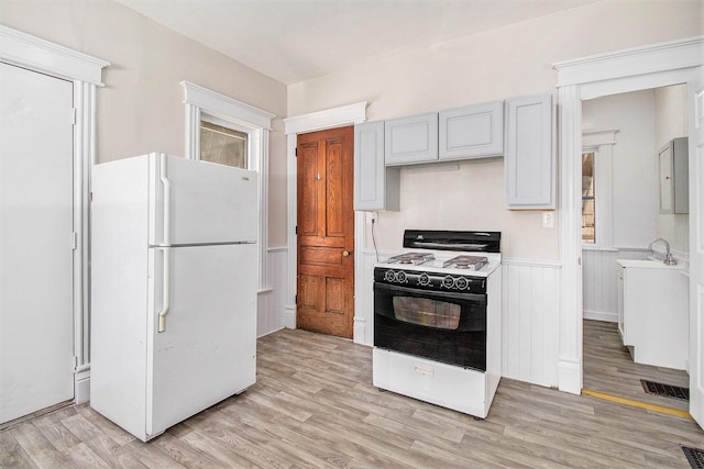 608 W Ransom St, Kalamazoo, MI 49007 - kitchen featuring white appliances, light wood-style floors, light countertops, and a wainscoted wall