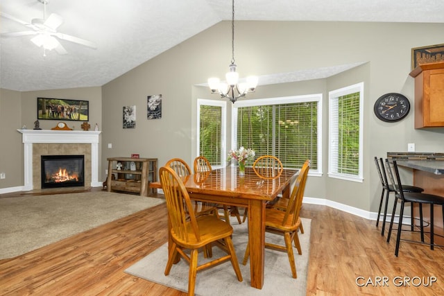 2808 Creekside Ct, Dorr, MI 49323 - dining space featuring vaulted ceiling, light wood-type flooring, a chandelier, a fireplace, and a ceiling fan