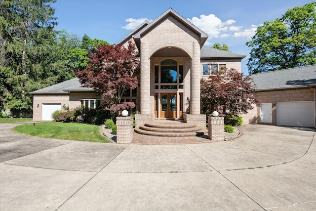 6076 Browns Lake Rd, Jackson, MI 49203 - traditional-style home with french doors, concrete driveway, brick siding, a front yard, and an attached garage
