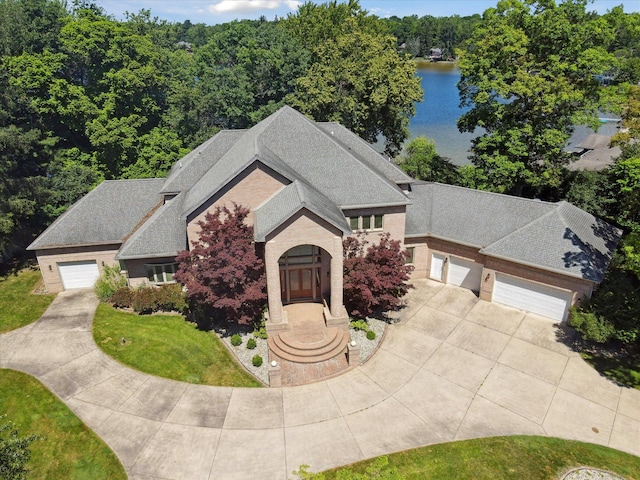 6076 Browns Lake Rd, Jackson, MI 49203 - view of front of home featuring driveway, a water view, a shingled roof, and a garage